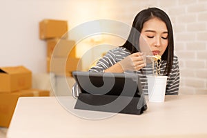 Asia freelance  business woman eating instant noodles while working on laptop in living room at home office at night. young Asian