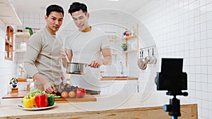Asia gay couple blogger vlogger and online influencer recording video content on healthy food in kitchen at home. Young LGBT men