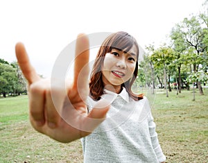 Asia girl shows the sign language to give love in the public park.