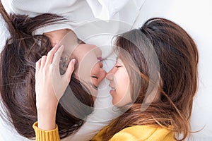 Asia lesbian LGBT Couple lay on bed and nose kiss with happiness