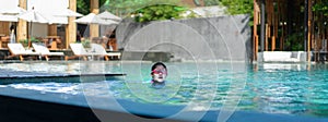 Asia little girl with googles swim in swimming pool in hotel resort beach front in holiday vacation