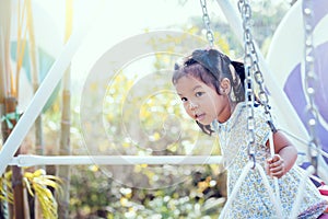 Asia little girl is playing swing at backyard in sunny day