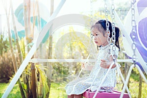 Asia little girl is playing swing at backyard in sunny day