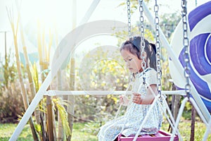 Asia little girl is playing swing at backyard in sunny day