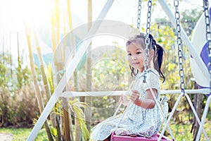Asia little girl is playing swing at backyard in sunny day