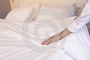 Asia maid making bed in hotel room, setting up pillow on bed