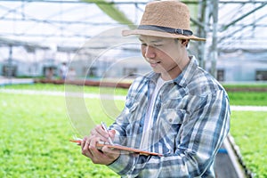 Asia man farmer inspecting the quality of organic vegetables grown using hydroponics.