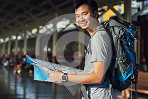 Asia man holding map with bag backpack alone in the train station, preparing,planing and find location for travel trip.