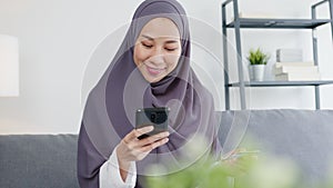Asia muslim lady use smart phone, credit card buy and purchase e-commerce internet in living room at house.