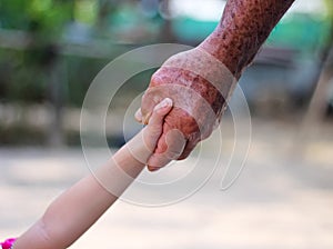 Asia old man hand holding young girl hand on background