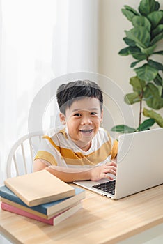 Asia preteen boy studying online on laptop with smiling and fun face at home. online education and e-learning concept