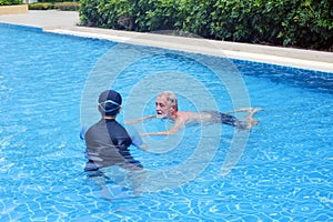 Portrait asia senior woman and caucasian old man resting together in the edge of swimming pool in clubhouse