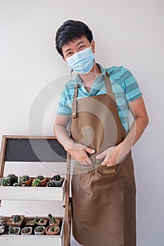 Asia SME small business owner job, Portrait of asian man wearing a mask standing with cactus tree in cafe owner