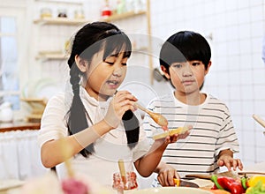 Asia two children are cooking food in the kitchen on a holiday in home.