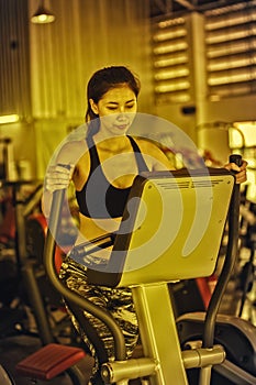 Asia woman doing exercise on elliptical trainer in fitness gym