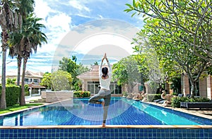 Asia woman doing yoga fitness exercise for relax and healthy beside swimming pool background. photo