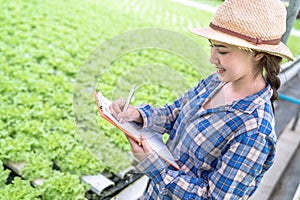 Asia woman farmer inspecting the quality of organic vegetables grown using hydroponics.