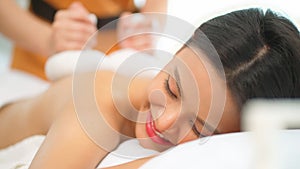 Asia woman lying down on spa bed and receive hot compress treatment in Thai spa on her back. Woman get a therapy massage for full