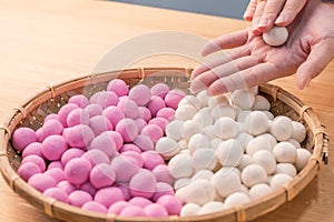 An Asia woman is making Tang yuan, yuan xiao, Chinese traditional food rice dumplings in red and white for lunar new year, winter