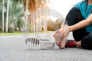 Asia woman massaging her painful foot while exercising. Running Sport and excercise injury concept