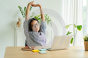 Asia woman  raised arm after sedentary with computer work in incorrect posture at desk, gesturing, Employees do light exercises at