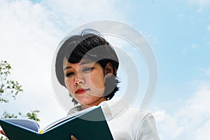 Asia woman reading and holding book on sky background