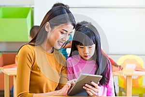 Asia woman teacher teach girl student with tablet computer in cl