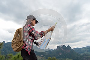 Asia woman traveler with backpack checks map to find directions in wilderness area, explorer.