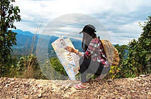 Asia woman traveler with backpack checks map to find directions in wilderness area, explorer.