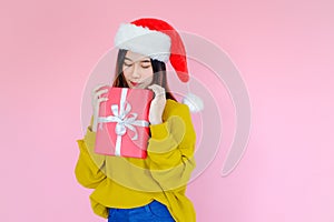 asia woman wearing long sleeve clothes on pink background with gift box in hand, Christmas or X'mas and happy new year