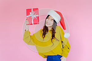 asia woman wearing long sleeve clothes on pink background with gift box in hand, Christmas or X'mas and happy new year