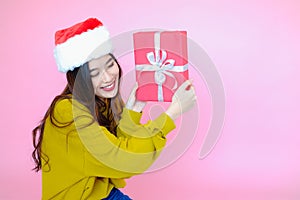 asia woman wearing long sleeve clothes on pink background with gift box in hand, Christmas or X'mas and happy new year