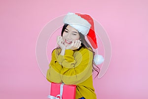 asia woman wearing long sleeve clothes on pink background with gift box in hand, Christmas or X'mas and happy new year