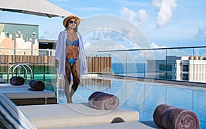 Asia women with a hat at a rooftop swimming pool at a luxury hotel