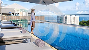 Asia women with a hat at a rooftop swimming pool at a luxury hotel