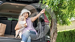 Asia women hugging her lovely puppy pomeranian dog at the back of suv car on travel tip and copy space