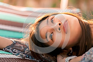 Woman lying on Beach Bed sun bathing with eye open to the sky, for summer relaxation concept