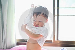 Asian 2 - 3 years old toddler boy child in bed concentrate on putting on his shirt, Encourage Self-Help Skills in Children