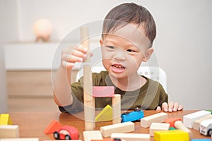 Asian 2 - 3 years old toddler boy child having fun playing with wooden building block toys indoor