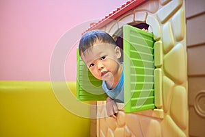 Asian 2 years old toddler boy child is playing peek a boo from the window of plastic toy house, Kids indoor playground, Indoor