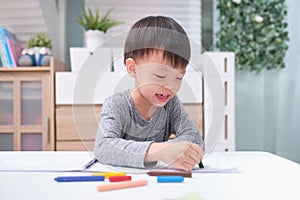 Asian 3 - 4 years old toddler boy child coloring with crayons at home, improve focus in child concept