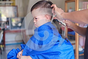 Asian 3 years old toddler baby boy child getting a haircut at the hairdresser`s barber shop