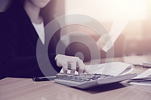 Asian accountant business woman working on desk and using calculator in office interior background