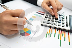 Asian accountant working and analyzing financial reports project accounting with chart graph and calculator in modern office,