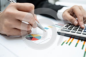 Asian accountant working and analyzing financial reports project accounting with chart graph and calculator in modern office,