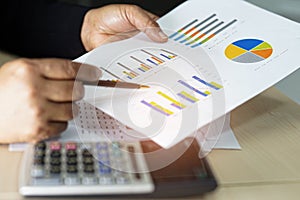 Asian accountant working and analyzing financial reports project accounting with chart graph and calculator in modern office