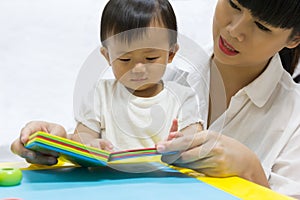 Asian adorable baby one year is looking book for kid.