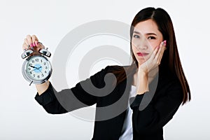 Asian adorable business woman with long hair wearing formal black suit, smiling, looking and holding alarm clock with isolated