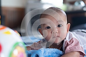 Asian Adorable infant baby lying on bed with toy Music Ball. Baby Child early development and activity Tummy time fun