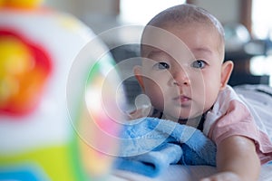 Asian Adorable infant baby lying on bed with toy Music Ball. Baby Child early development and activity Tummy time fun